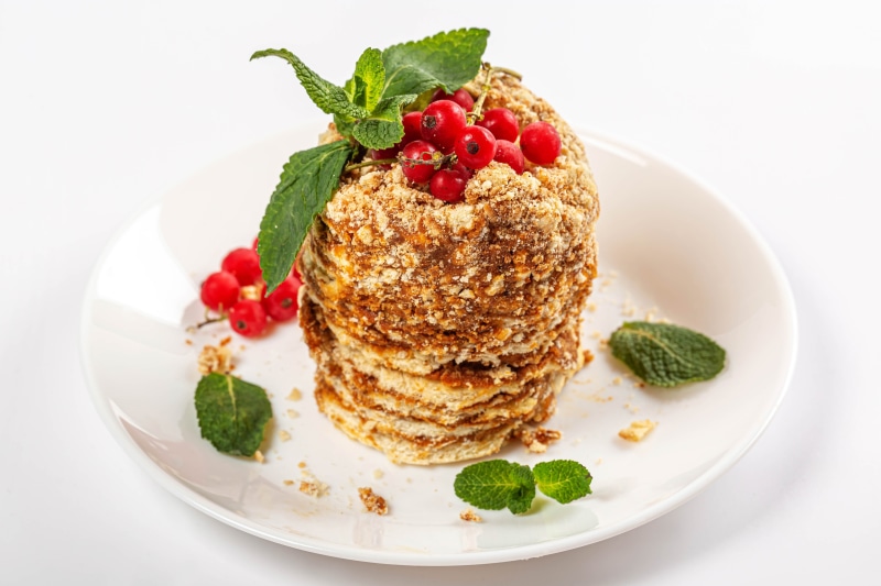 Honey cake with currants and mint on a white plate