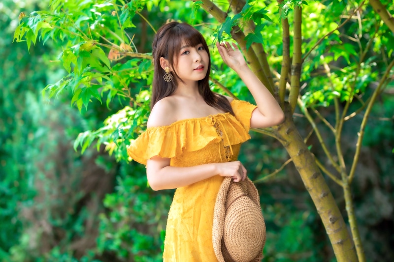 Asian woman in yellow dress holding a hat
