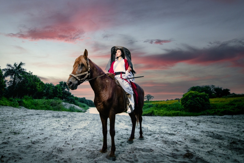Woman in traditional Asian attire riding a horse