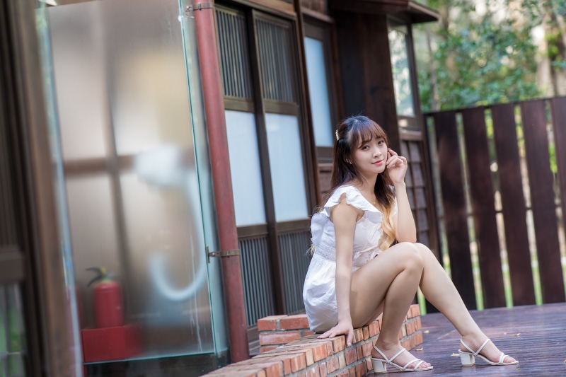 Asian woman in white dress sitting outdoors