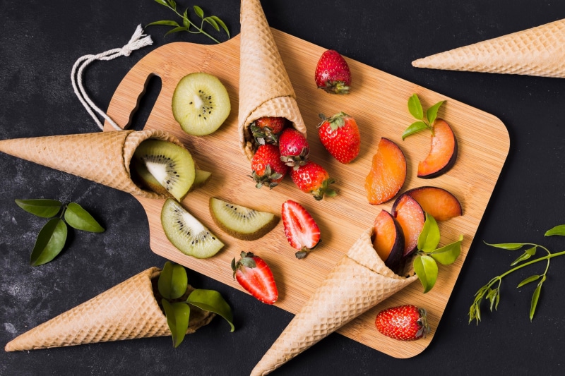 Strawberries, Kiwis, and Plums in Ice Cream Cones on Cutting Board