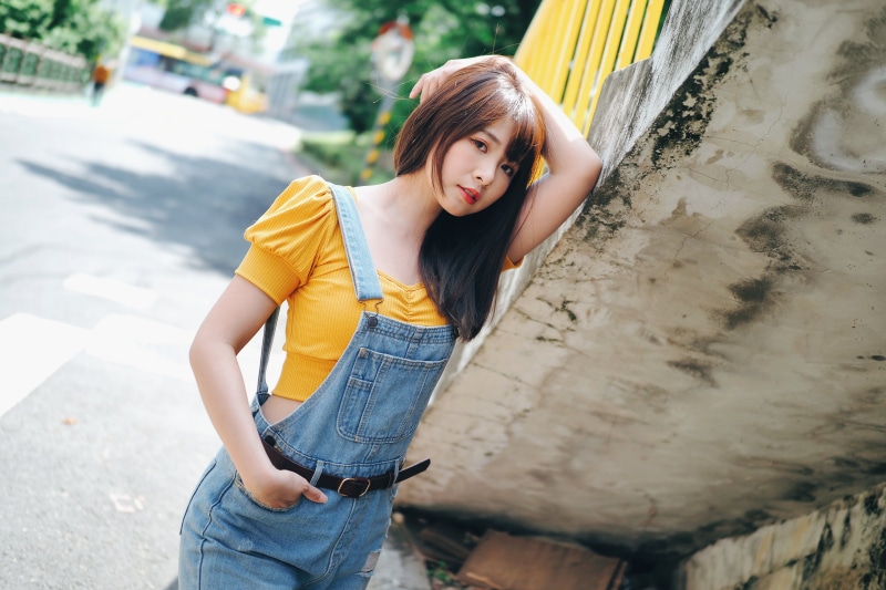 Asian woman in denim overalls and yellow top