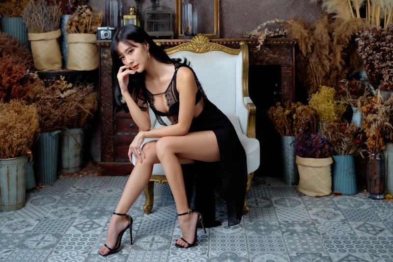 Asian woman in black dress sitting on armchair