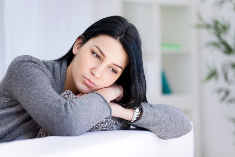 Brunette girl in sweater with hands on couch