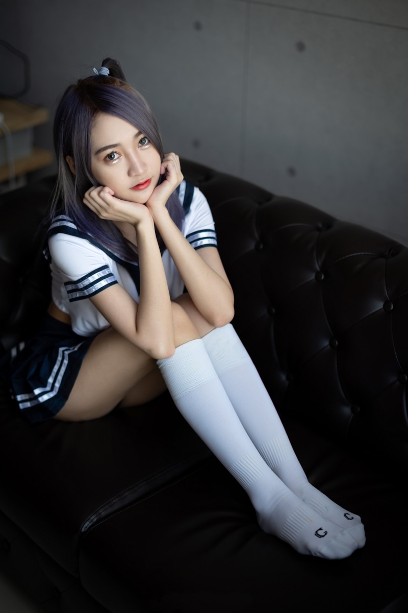 Asian girl in school uniform sitting on a couch