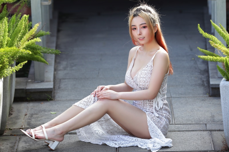 Asian woman sitting on pavement in a dress