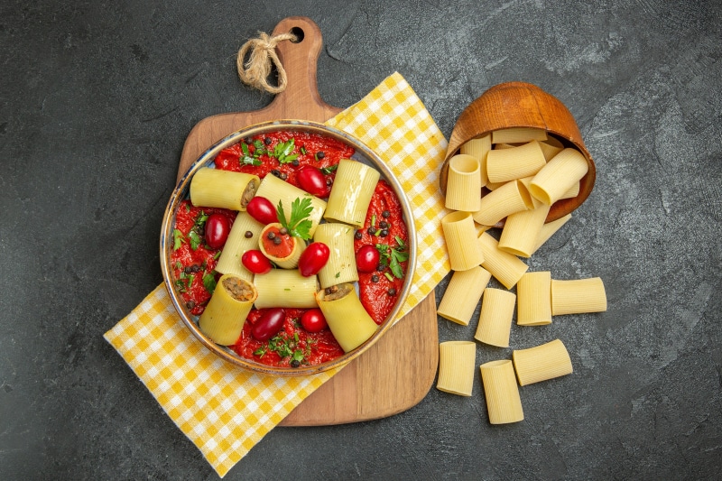 Pasta with tomato sauce and dogwood berries on a cutting board