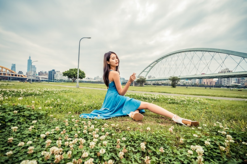Asian woman in blue dress sitting on grass
