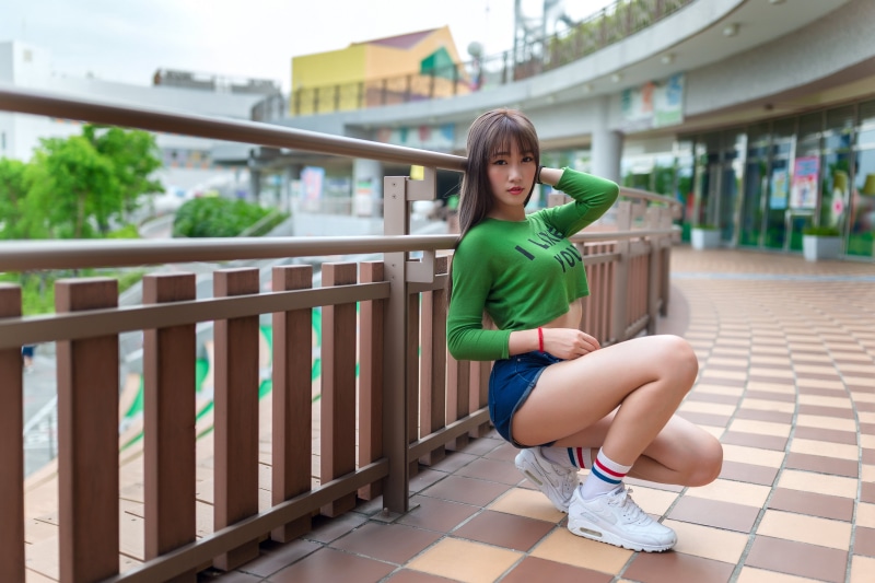 Asian woman in green crop top and denim shorts posing