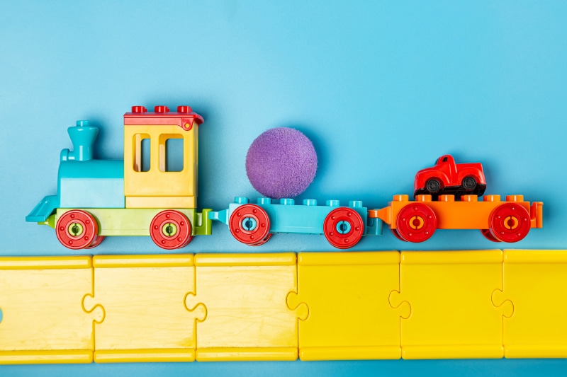 Toy train with ball and car on tracks