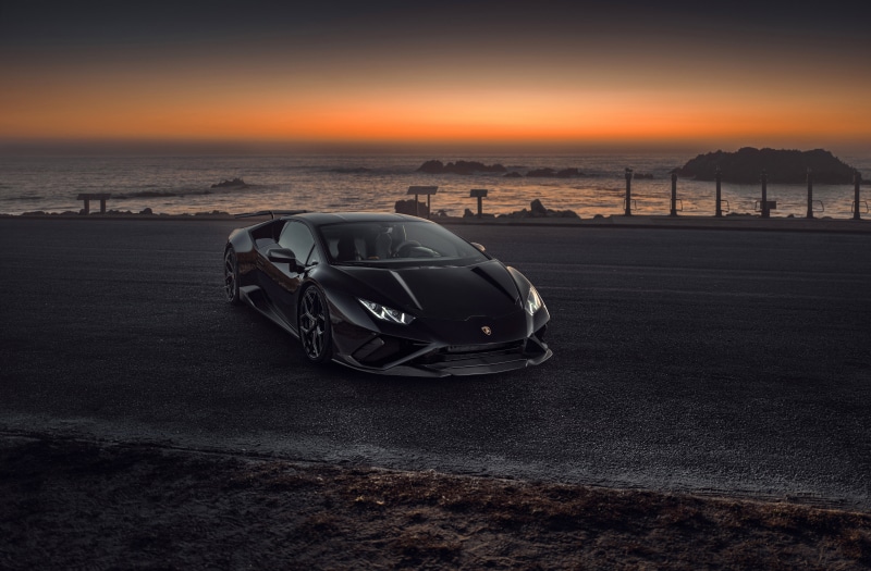 Black Lamborghini Coupe on Road by Ocean at Sunset
