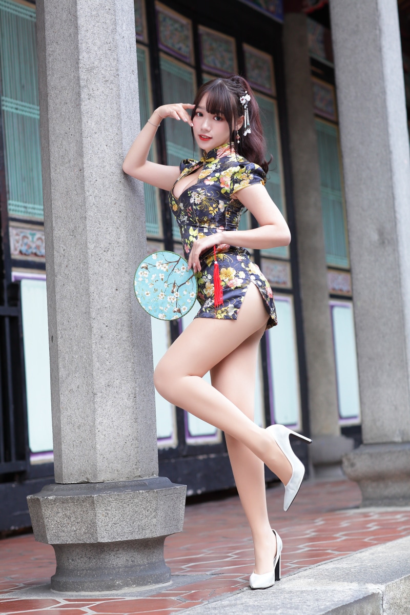 Woman in a floral dress holding a hand fan