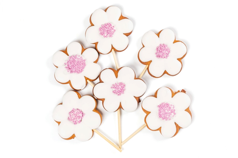Flower-shaped cookies with pink sprinkles on sticks
