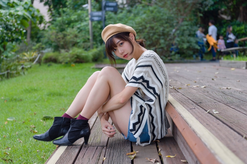 Asian woman wearing beret sitting on wooden steps