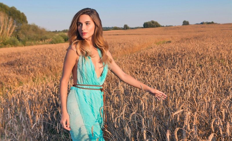 Woman in a blue dress in a wheat field