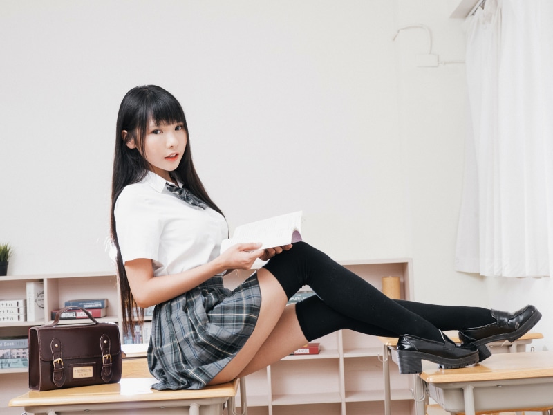 Brunette girl in school uniform reading a book