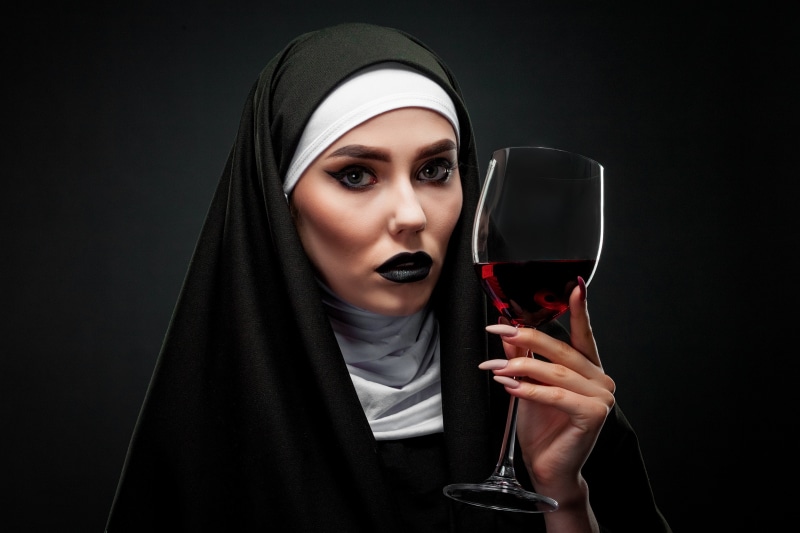 Woman in nun habit holding wine glass