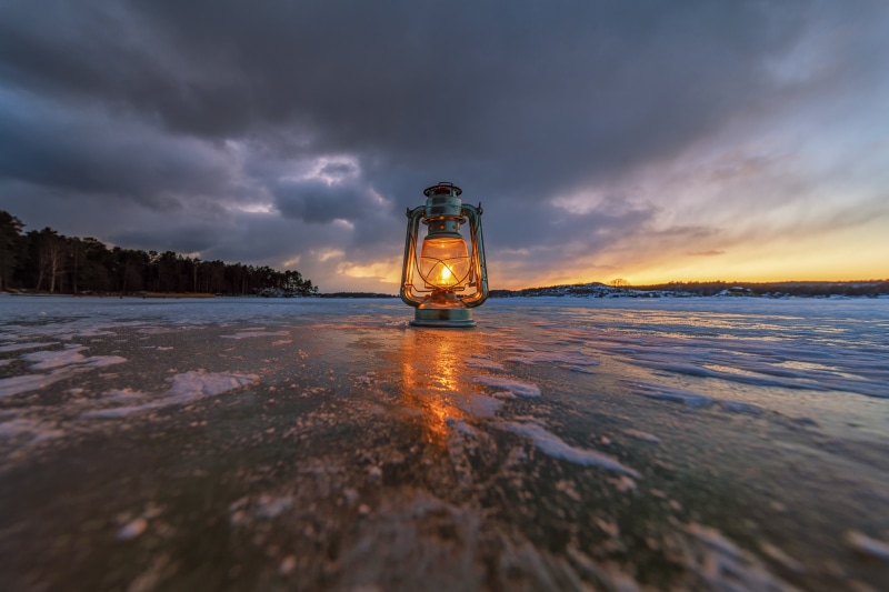 Kerosene lamp on ice at sunset
