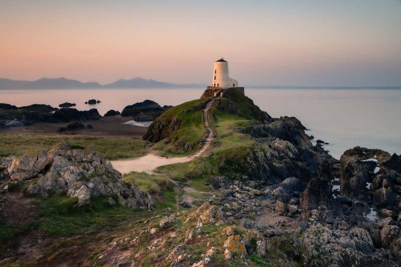 Lighthouse on a rocky coast in Wales at sunset