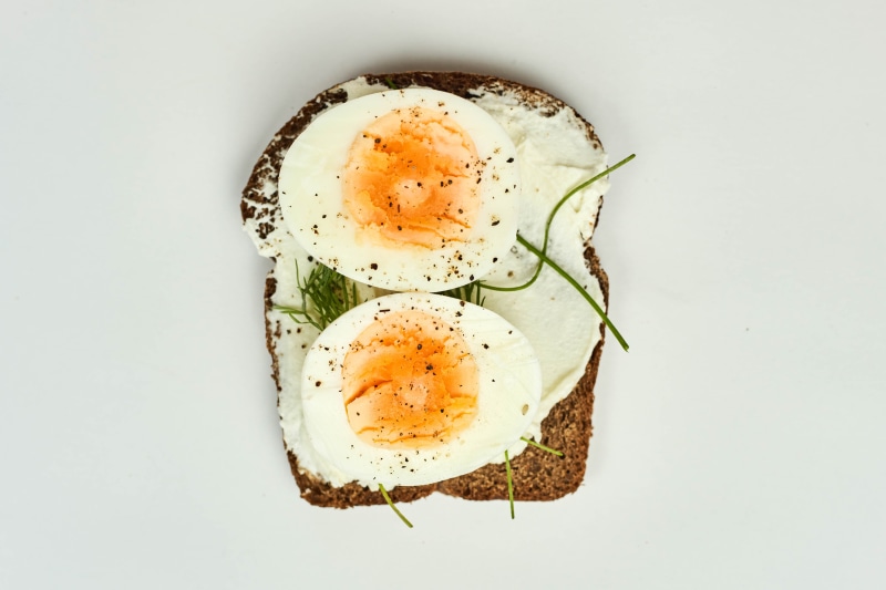 Open-faced sandwich with cream cheese, hard-boiled eggs, and herbs