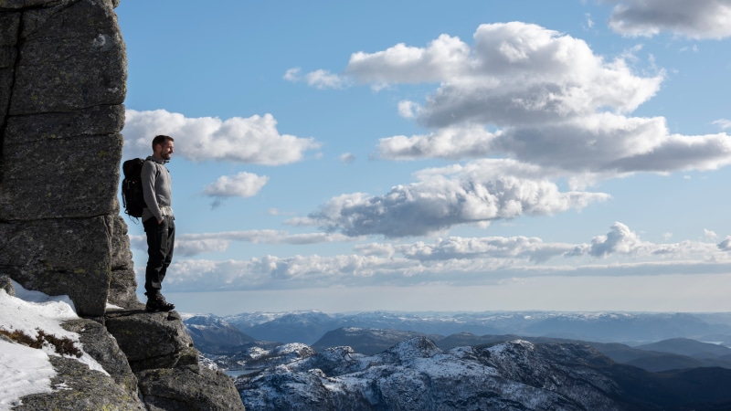 Man with backpack on a rocky cliff in Norway