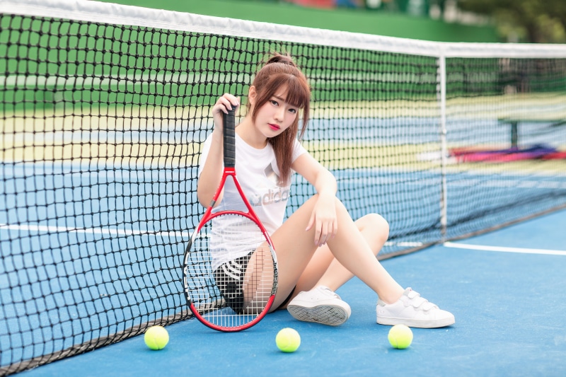 Asian woman with tennis racket on court