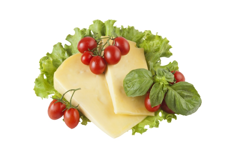 Cheese slices with cherry tomatoes and basil on lettuce