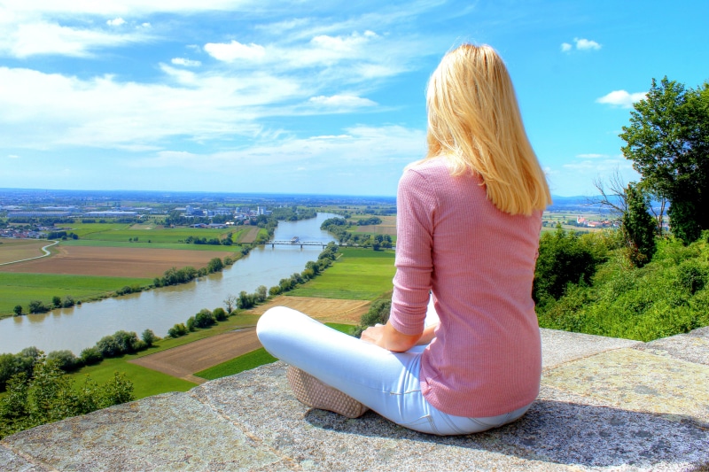 Blonde girl sitting in lotus position overlooking a river in Germany