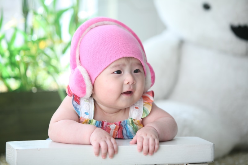 Baby wearing pink headphones and hat