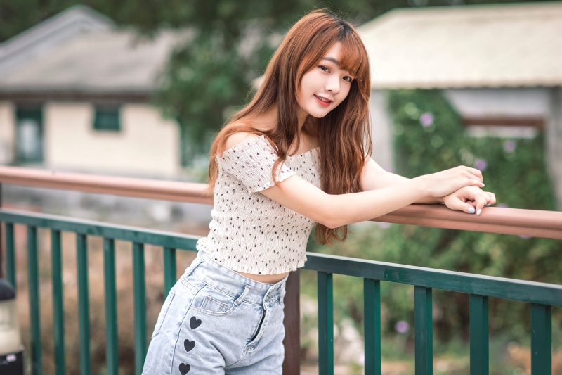 Asian woman in off-the-shoulder blouse and denim shorts