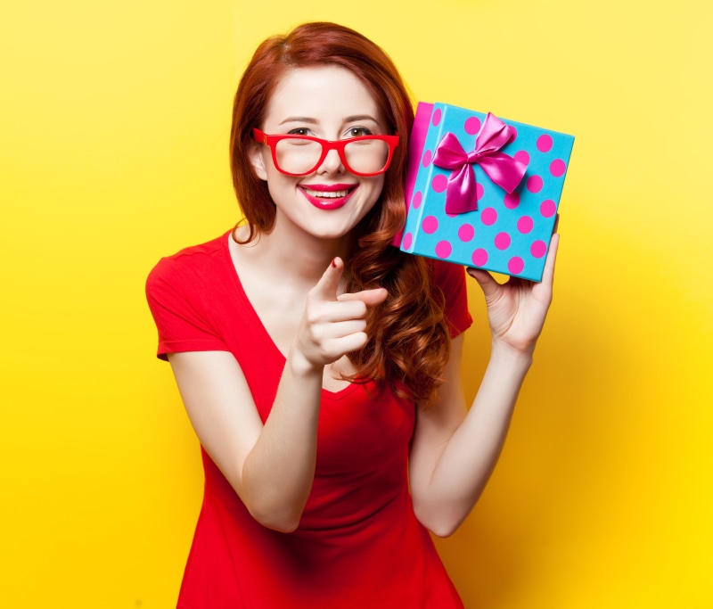 Redhead girl with glasses holding a gift