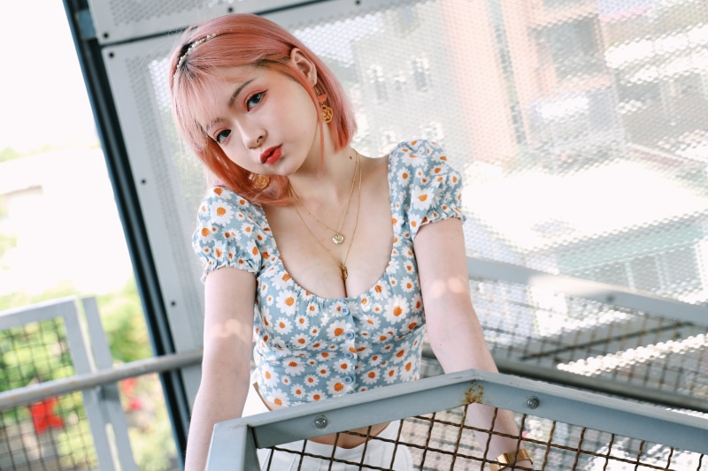 Asian woman with pink hair wearing a floral blouse