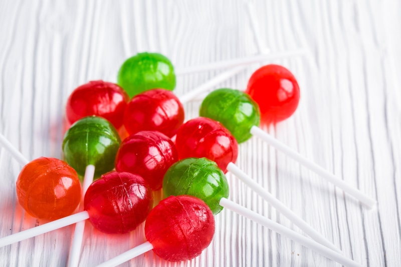 Many colorful lollipops on a white wooden surface