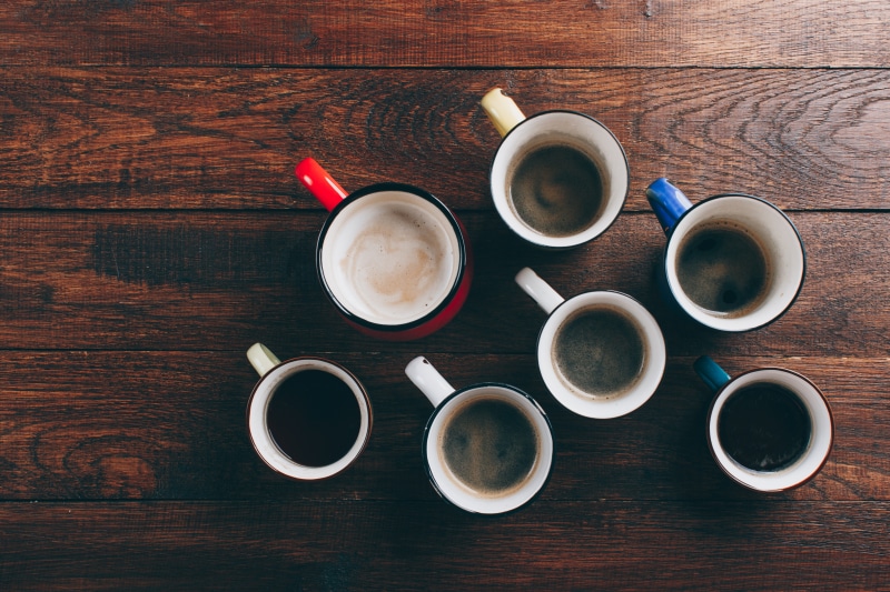 Several cups of coffee on wooden planks