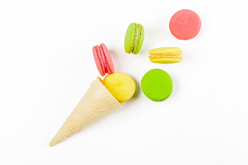 Ice cream cone with macarons on white background