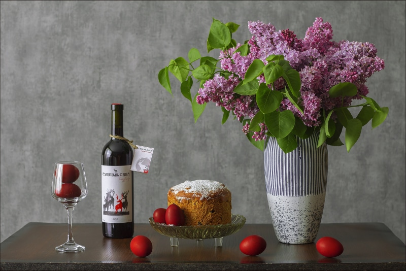 Easter still life with wine, kulich, eggs, and lilac