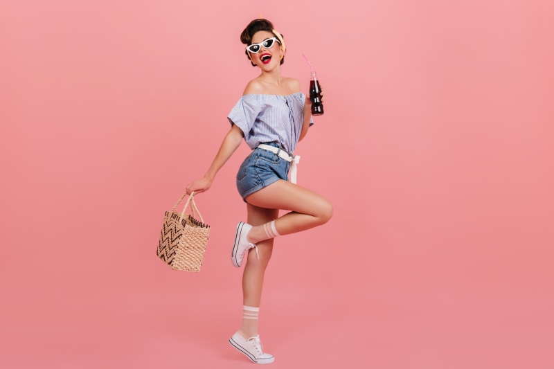 Woman in shorts holding a bottle and handbag