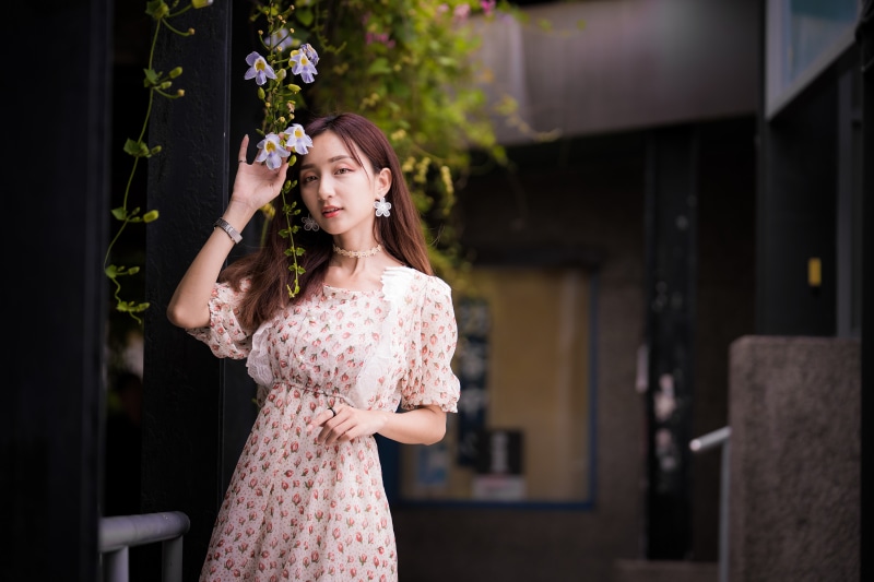 Asian woman in floral dress near flowers