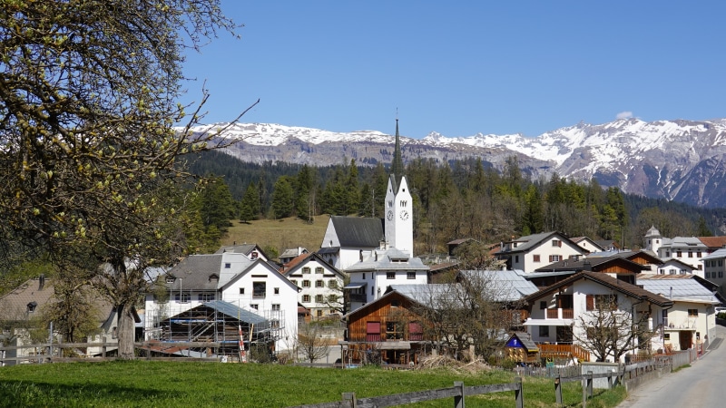 Village with Church and Snow-Capped Mountains in Switzerland
