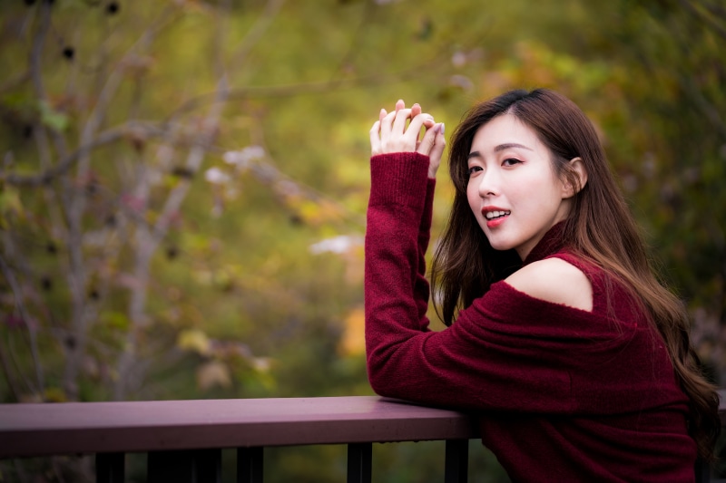 Asian woman in maroon sweater with bokeh background