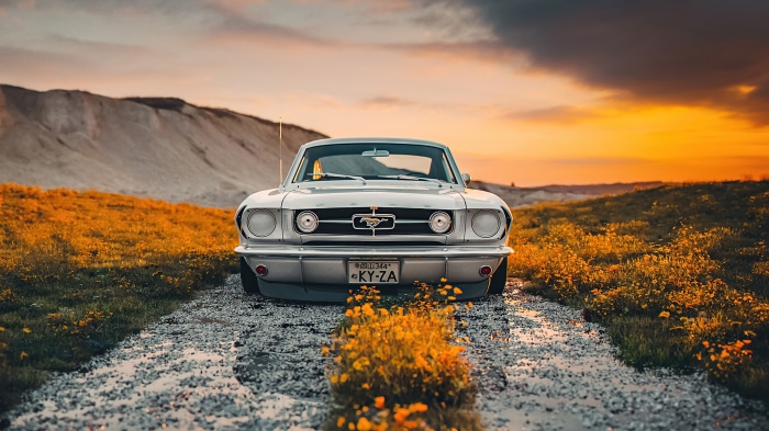Classic Ford Mustang on a dirt road at sunset