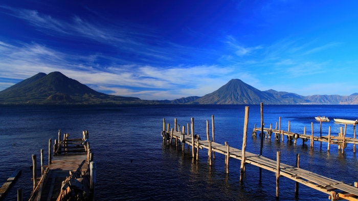 Wooden piers on a lake with mountains and blue sky 4K