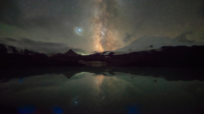 Milky Way over mountains reflected in a lake at night 4K