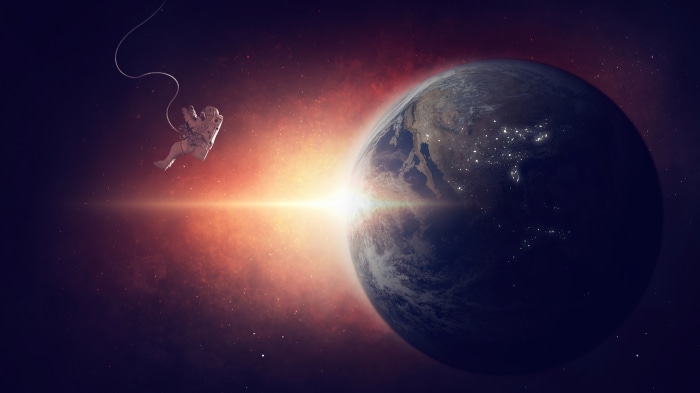 Astronaut floating in space with Earth and sun