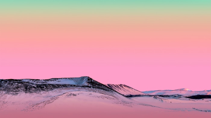 Snowy mountains under a pink and green sky