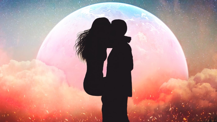 Couple silhouette kissing under a large moon in a starry sky