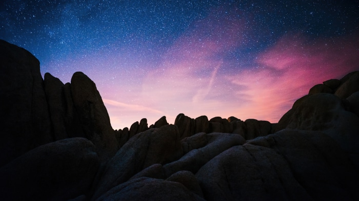 Rock formations under a starry sky at sunrise in California