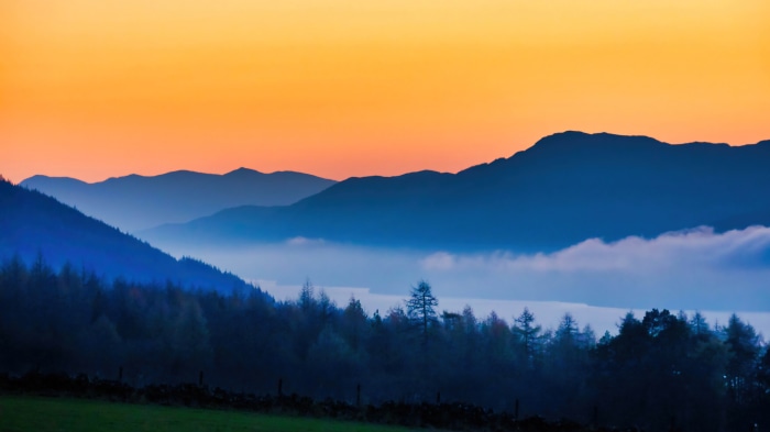 Mountain range with fog and forest at sunset 4K