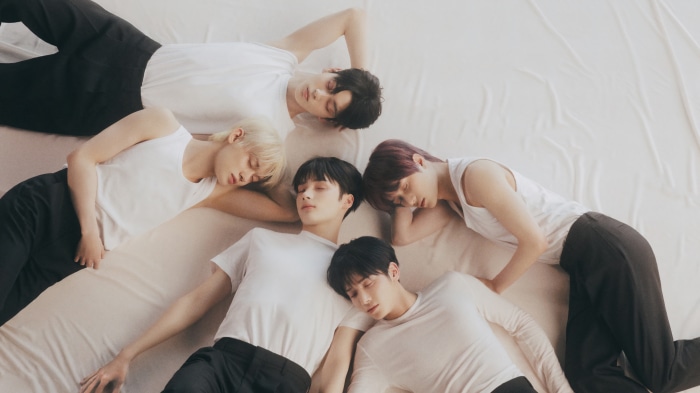 Tomorrow X Together members sleeping on a white sheet