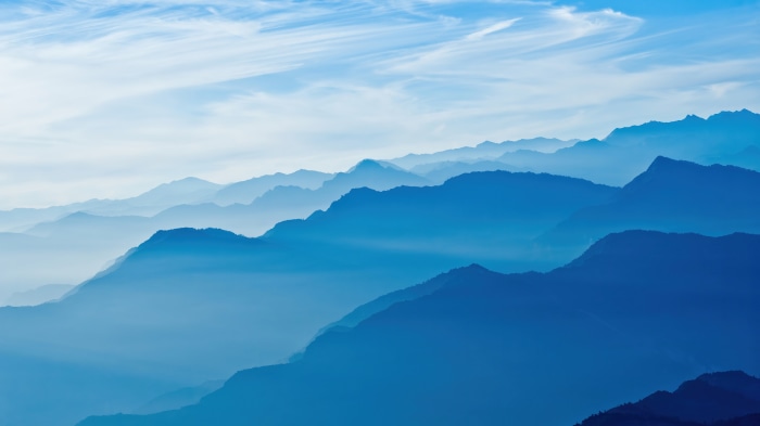 Layered blue mountains under a cloudy sky